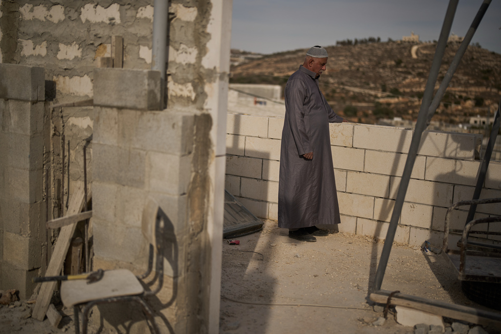 Mahmoud Tubasi stands on a rooftop near his two family's houses, which were burned by Israeli settlers in the West Bank village of Jalud, Tuesday, Oct. 20, 2026. (AP Photo/Leo Correa)