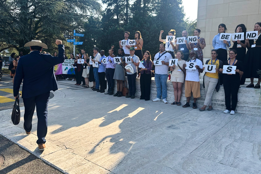 Panama Climate Envoy Juan Carlos Monterrey Gomez, left, cheers on environmentalists and Indigenous leaders holding signs against plastic pollution in front of the United Nations building in Geneva, Switzerland, Tuesday, Aug. 12, 2025. (AP Photo/ Jennifer McDermott)