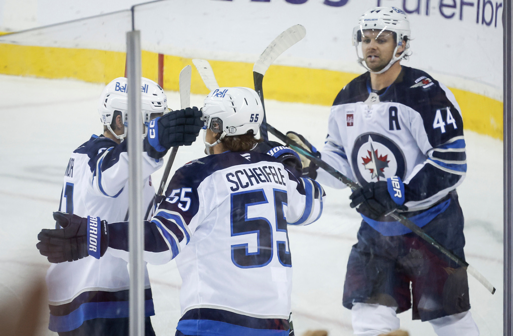 Winnipeg Jets' Mark Scheifele, centre, celebrates his goal with teammates during third period NHL hockey action against the Calgary Flames in Calgary, Alta., Monday, Oct. 20, 2025. (Jeff McIntosh/The Canadian Press via AP)