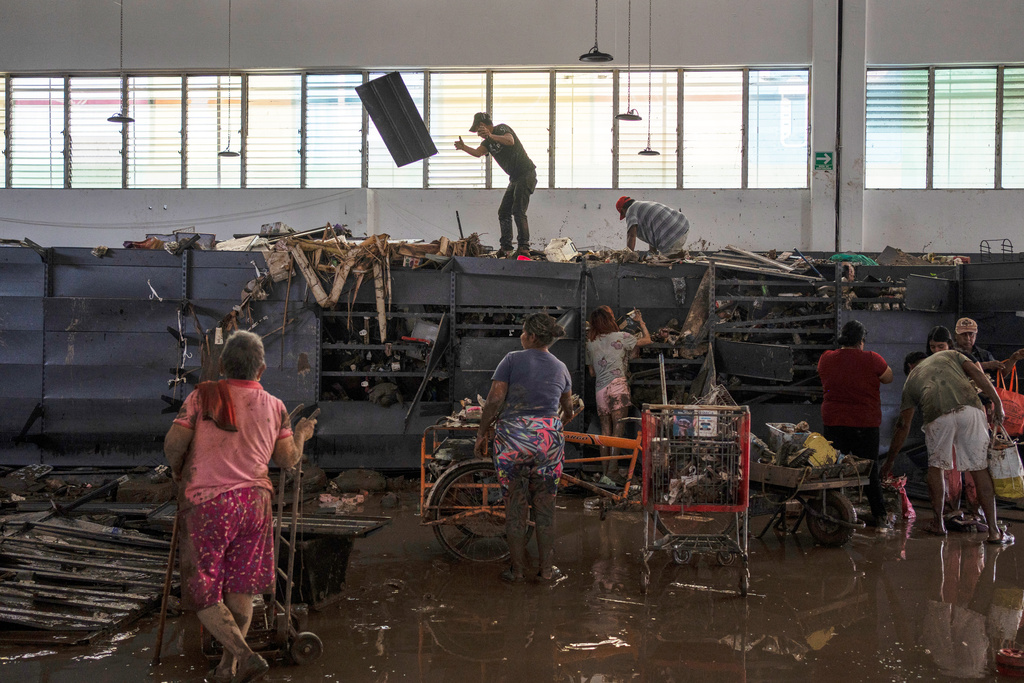 People loot a supermarket damaged by heavy rainfall in Poza Rica, Veracruz state, Mexico, Saturday, Oct. 11, 2025. (AP Photo/Felix Marquez)