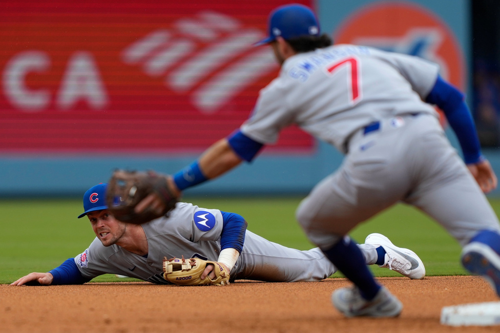 Chicago Cubs second baseman Nico Hoerner, left, watches his throw to shortstop Dansby Swanson to force out Los Angeles Dodgers' Max Muncy at second on a fielder's choice hit by Kyle Tucker during the second inning of a baseball game Saturday, April 25, 2026, in Los Angeles. (AP Photo/Mark J. Terrill)