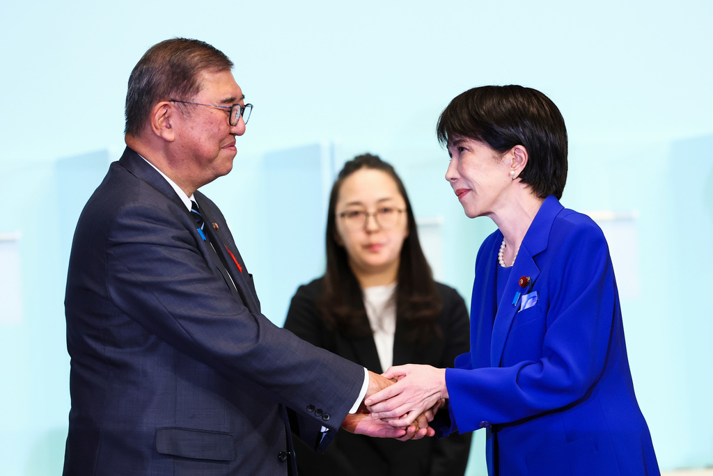 Newly-elected leader of Japan's Liberal Democratic Party (LDP) Sanae Takaichi, right, shakes hands with Prime Minister Shigeru Ishiba after winning the LDP leadership election i in Tokyo, Japan, Saturday, Oct. 4, 2025. (Kim Kyung-Hoon/Pool Photo via AP)