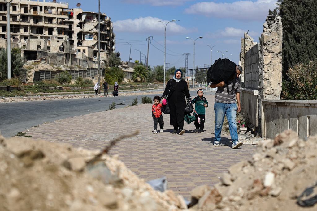 Residents leave the Sheikh Maqsoud and Achrafieh neighborhoods of Aleppo, Syria, Tuesday, Oct. 7, 2025, following overnight clashes between Syrian government troops and the Kurdish-led Syrian Democratic Forces. (AP Photo/Omar Albam)