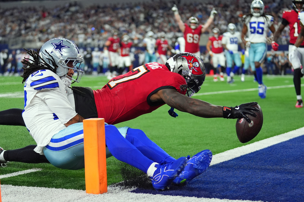 Tampa Bay Buccaneers running back Bucky Irving (7) dives past Dallas Cowboys defensive back Reddy Steward (27) for a touchdown in the first half of an NFL football game in Arlington, Texas on Thursday, Oct. 8, 2026. (AP Photo/Julio Cortez)