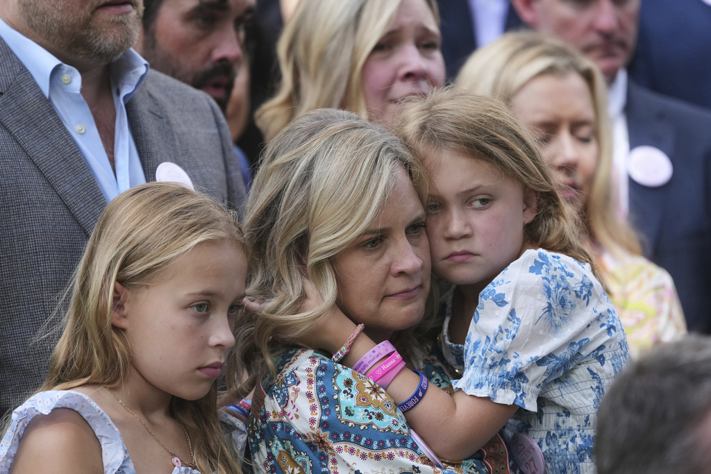 Carrie Hanna stands with her daughters Hunter, right, and Harper, left, and other parents and family of children who died at Camp Mystic, as they watch Texas Gov. Greg Abbott sign camp safety bills, Friday, Sept. 5, 2025, in Austin, Texas. (AP Photo/Eric Gay)