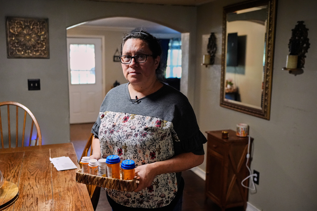 Celia Monreal holds some of her and her husband's medications as she poses for a photo at their home Wednesday, Oct. 8, 2025, in Tyler, Texas. (AP Photo/Tony Gutierrez)