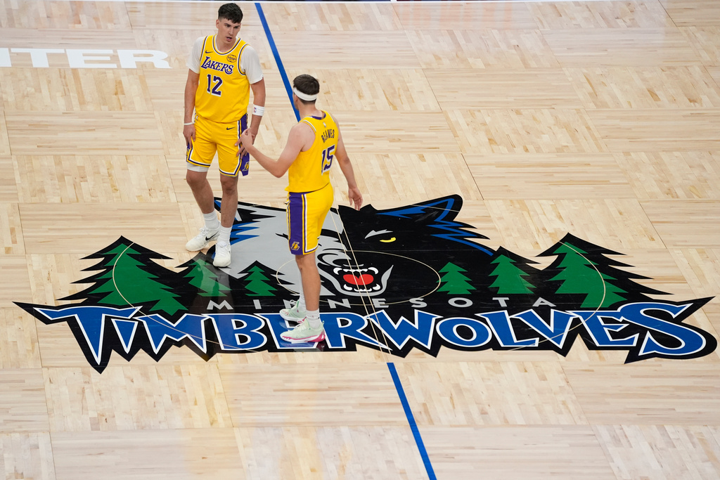 Los Angeles Lakers forward Jake LaRavia (12) and guard Austin Reaves (15) talk during the first half of an NBA basketball game against the Minnesota Timberwolves, Wednesday, Oct. 29, 2025, in Minneapolis. (AP Photo/Abbie Parr)