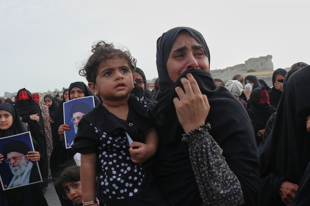 A woman carrying a child weeps during a mass funeral for people killed when, according to Iranian media and a rights group, a U.S. missile struck a home where a wedding was being held in Kuhestak, southern Iran, Thursday, Sept. 3, 2026. (Razieh Poudat/ISNA via AP)