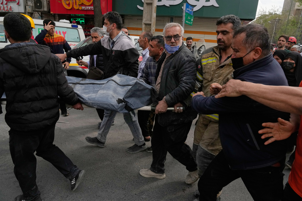 FILE - The body of a victim is carried away as a relative tries to get closer after being recovered from a residential building that was hit overnight by an air strike in Tehran, March 27, 2026. (AP Photo/Vahid Salemi, File)