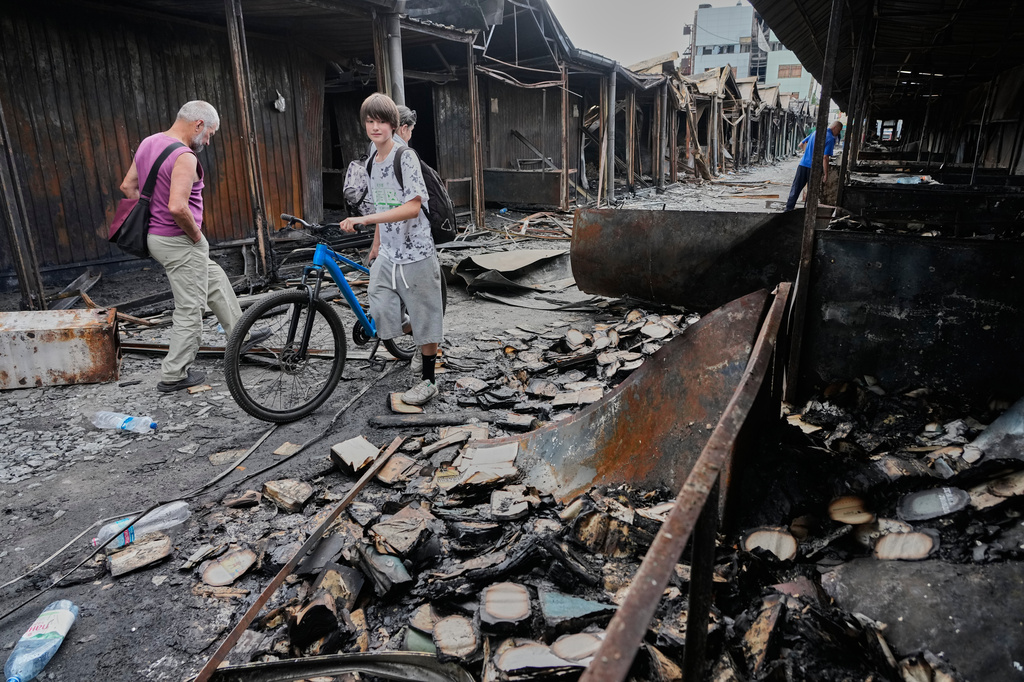 People search for survived books after the fire on the site of the country's biggest book market, cased by Russia's recent missile attack in Kyiv, Ukraine, Wednesday, Aug.19, 2026. (AP Photo/Efrem Lukatsky)