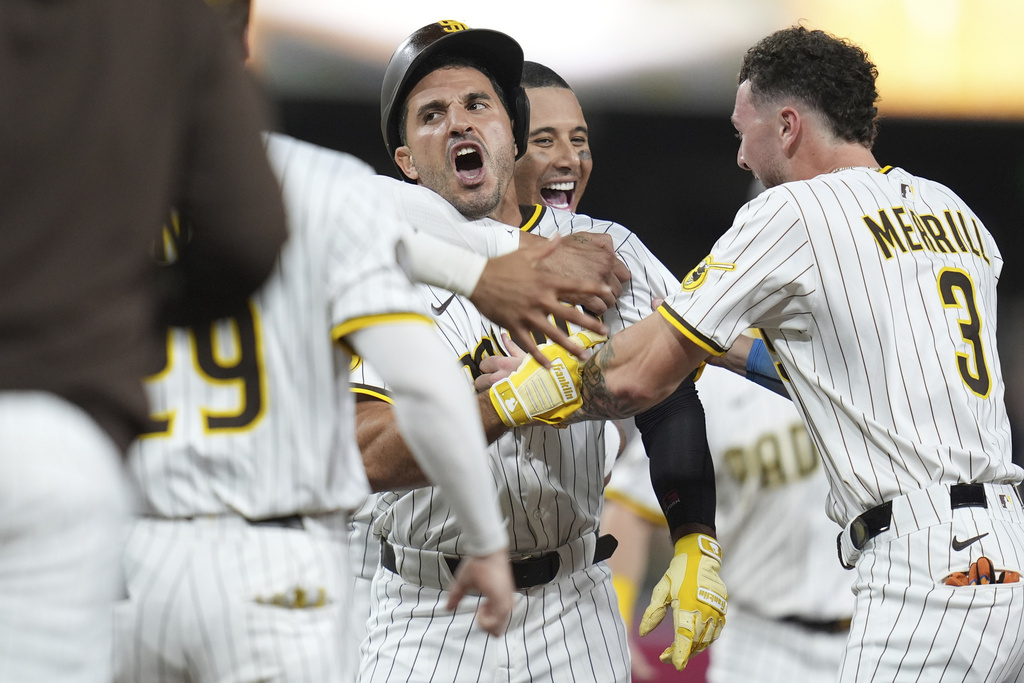 San Diego Padres' Ramon Laureano, center, is swarmed by teammates after hitting a walk-off RBI single during the tenth inning of a baseball game Saturday, Aug. 9, 2025, in San Diego. The Padres won 5-4. (AP Photo/Gregory Bull)