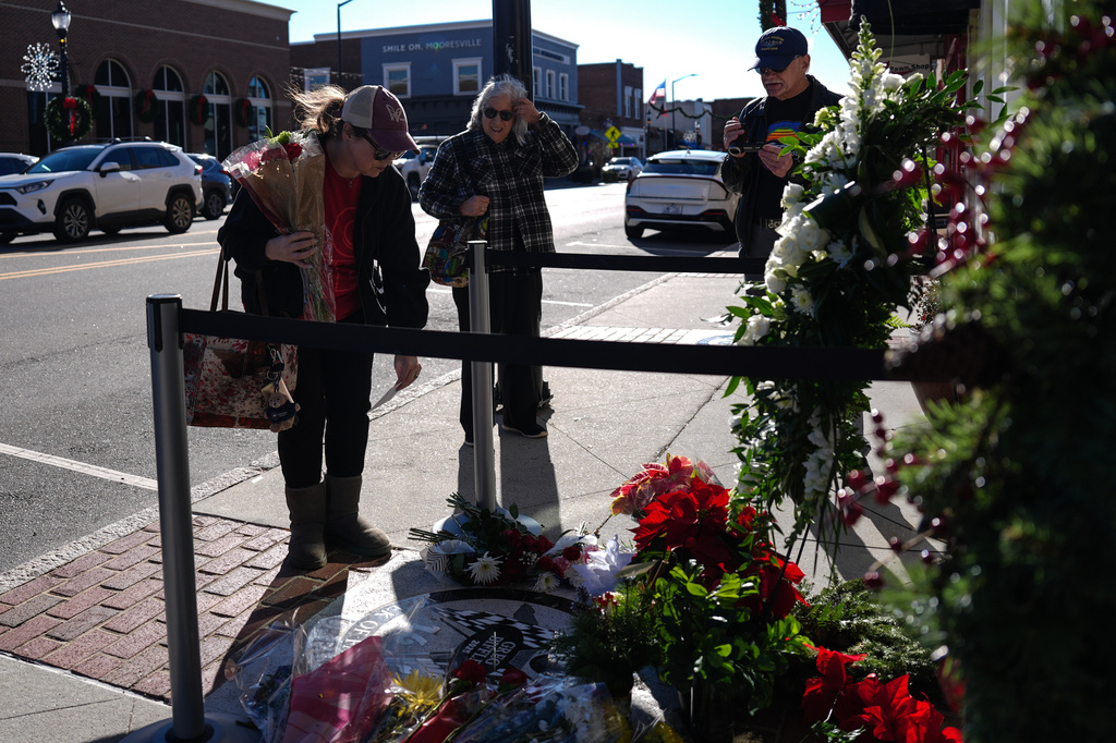 Nicole O'Healy, left, leaves flowers at the NC Auto Racing Walk of Fame for Greg Biffle, Friday, Dec. 19, 2025, in Mooresville, N.C. (AP Photo/Matt Kelley)