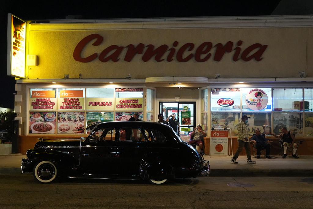 A vintage lowrider is parked in front of a butcher's shop at the 6th Annual Lady Lowrider Cruise Night in celebration of International Women's Day in Pasadena, Calif., on Sunday, March 8, 2026. (AP Photo/Damian Dovarganes)