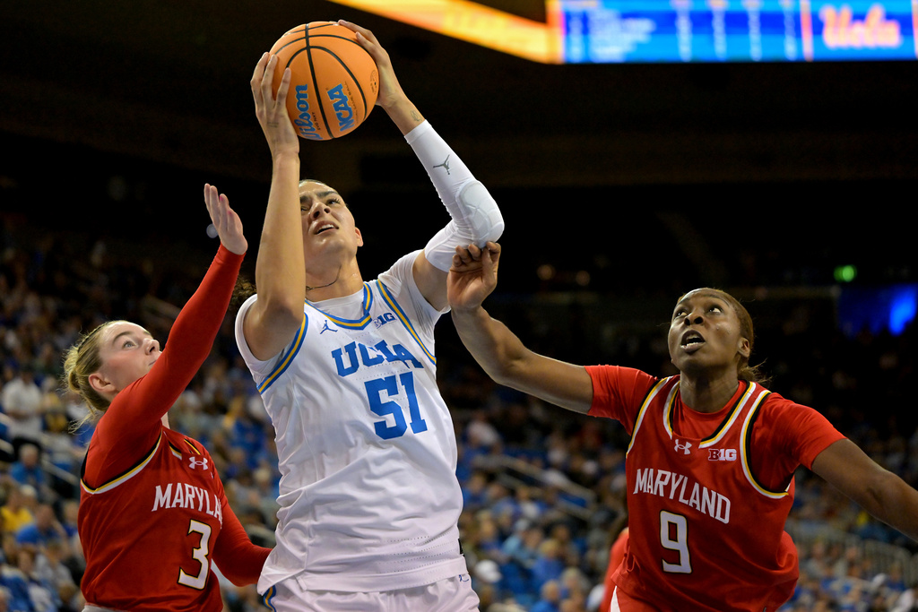 UCLA center Lauren Betts (51) is defended by Maryland guard Addi Mack, left, and forward Isimenme Ozzy-Momodu as she drives to the basket during the first half of an NCAA college basketball game Sunday, Jan. 18, 2026, in Los Angeles. (AP Photo/Jayne Kamin-Oncea)
