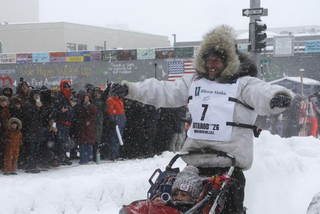 Jessie Holmes, the defending Iditarod Trail Sled Dog Race champion, acknowledges crowds on both side of Fourth Avenue during the ceremonial start for this year's race in downtown Anchorage, Alaska, on Saturday, March 7, 2026. (AP Photo/Mark Thiessen)