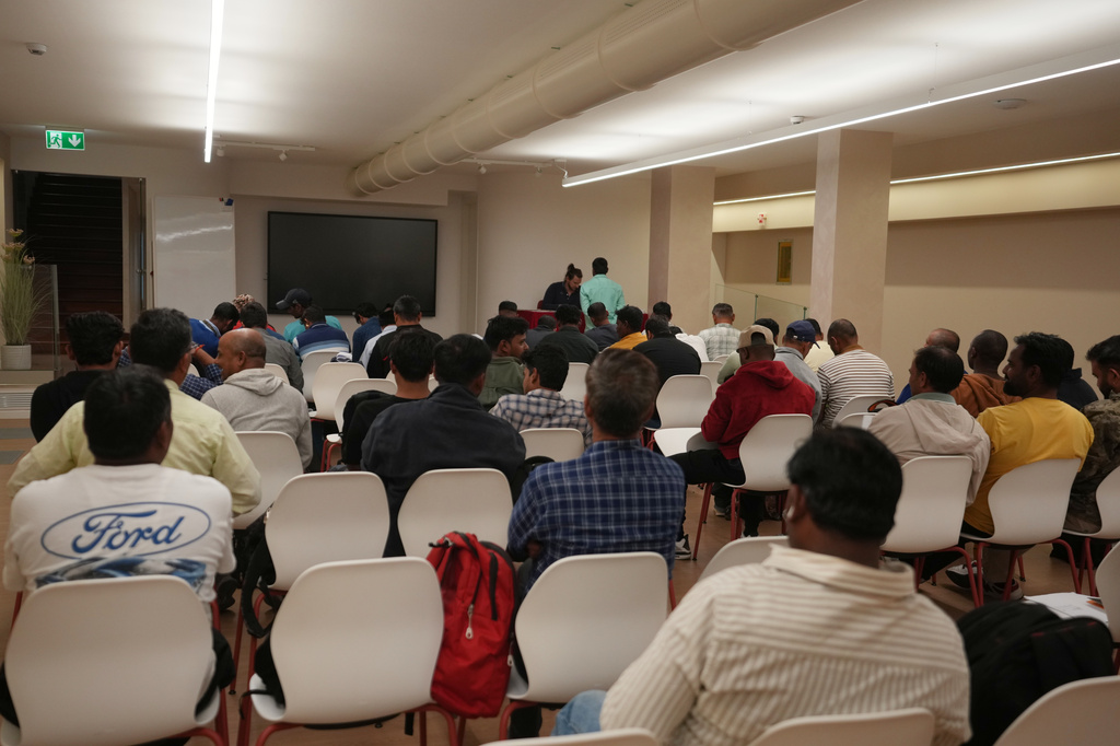 Caddell workers gather in a hotel conference room to wait their turn to sign an agreement for compensation from the U.S. construction company Caddell as part of a settlement into illegal labor practices at a building site for a new U.S. consulate compound in Milan, Italy, Wednesday, Oct. 7, 2026. (AP Photo/Luca Bruno)