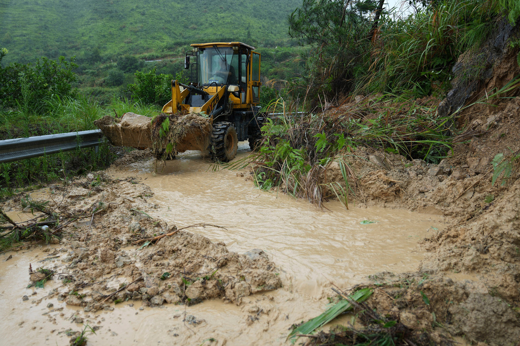 In this photo released by Xinhua News Agency, a worker drives an excavator to clear a road blocked by small-scale landslides in a village in Qiangtian County, Lishui City, eastern China's Zhejiang Province, July 12, 2026. (Han Chuanhao/Xinhua via AP)
