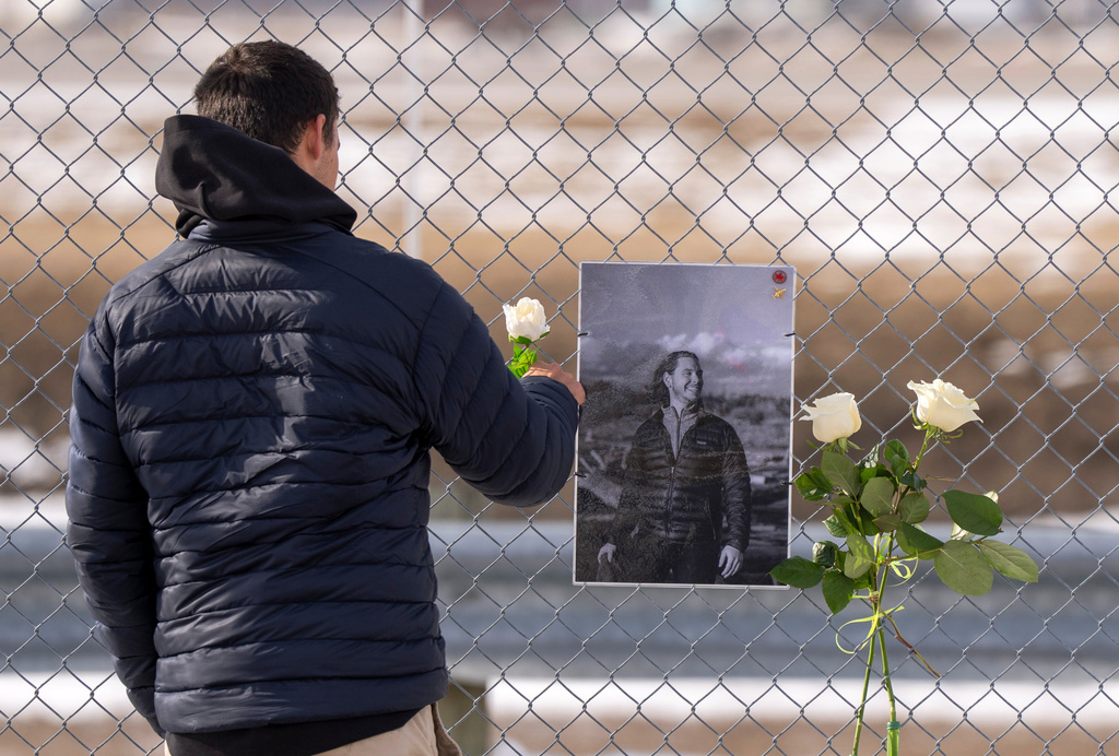 A man places a white rose on the memorial for Air Canada Jazz pilot Antoine Forest, who perished when his plane collided with an emergency vehicle at New York's LaGuardia Airport, in Montreal, Wednesday, March 25, 2026. (Christinne Muschi/The Canadian Press via AP)