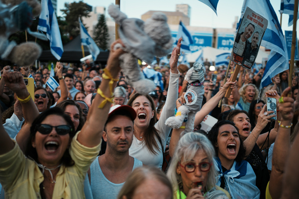 People react as they gather to watch a live broadcast of Israeli hostages released from Gaza at a plaza known as hostages square in Tel Aviv, Israel, Monday, Oct. 13, 2025. (AP Photo/Emilio Morenatti)