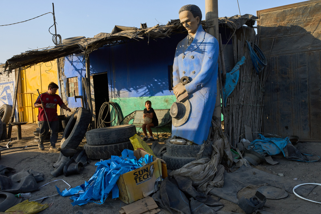 A man works at a tire shop adorned with a statue of Peruvian poet Cesar Vallejo in the El Milagro district of Trujillo, Peru, Sunday, May 16, 2026. (AP Photo/Rodrigo Abd)