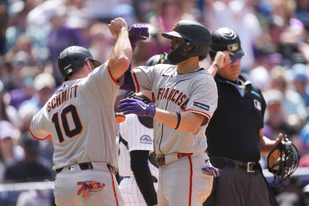 San Francisco Giants' Casey Schmitt, left, congratulates Willy Adames, front right, crosses home plate after hitting a grand slam off Colorado Rockies relief pitcher Zach Agnos in the fifth inning of a baseball game Sunday, May 31, 2026, in Denver. (AP Photo/David Zalubowski)
