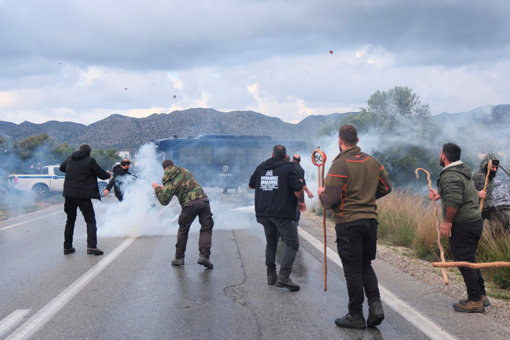 Farmers throw stones at police during clashes with officers blocking their march to Chania's airport on Crete, Greece, Monday, Dec. 8, 2025, amid protests over delayed EU farm subsidies. (AP Photo/Giannis Angelakis)