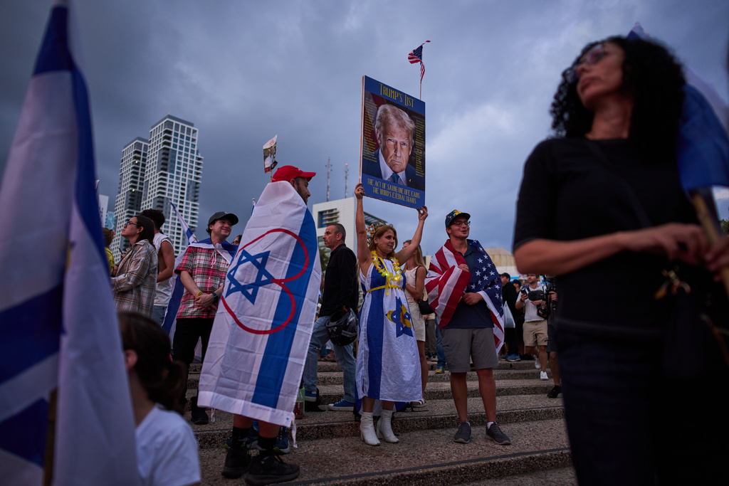 A woman holds an image of U.S. President Donald Trump during a gathering at a plaza known as hostages square in Tel Aviv, Israel, Monday, Oct. 13, 2025, before the release of Israeli hostages held in Gaza. (AP Photo/Oded Balilty)