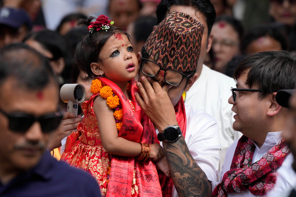 Nepal's newly appointed living goddess, Kumari Aryatara Shakya, is carried by her father as they walk towards Kumari Ghar, the temple palace where she will be residing in Kathmandu, Nepal, Tuesday, Sept. 30, 2025. (AP Photo/Niranjan Shrestha)