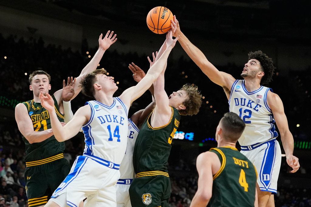 Duke's Cameron Boozer (12) and Nikolas Khamenia (14) battle for the ball with Siena's Riley Mulvey (55), Brendan Coyle (21) and Gavin Doty (4) during the first half in the first round of the NCAA college basketball tournament, Thursday, March 19, 2026, in Greenville, S.C. (AP Photo/Brynn Anderson)