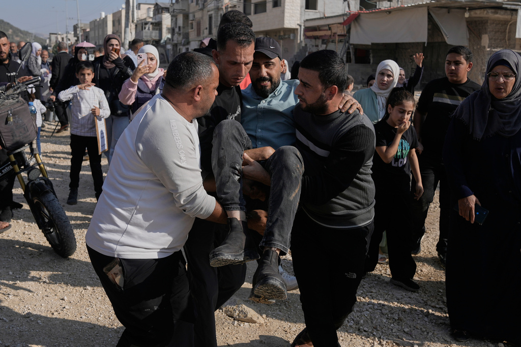 Al Jazeera cameraman Fadi Yassin is carried after being shot in the legs by Israeli soldiers during a protest by displaced Palestinians calling to return to their houses in the Nur Shams refugee camp, in the West Bank city of Tulkarem, Tuesday, Nov. 18, 2025. (AP Photo/Majdi Mohammed)
