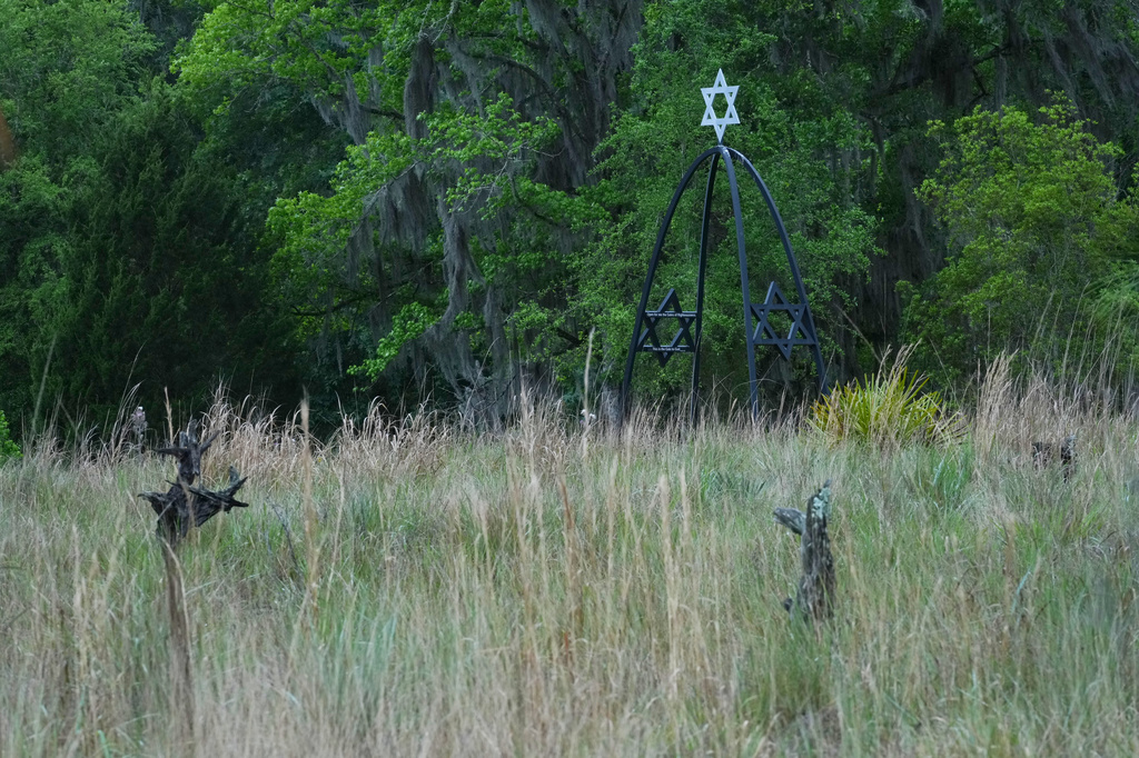 An arch leading to the Jewish burial site rises over grave markers on a field of native grasses at the Prairie Creek Conservation Cemetery, Tuesday, April 7, 2026, in Gainesville, Fla. (AP Photo/Marta Lavandier)