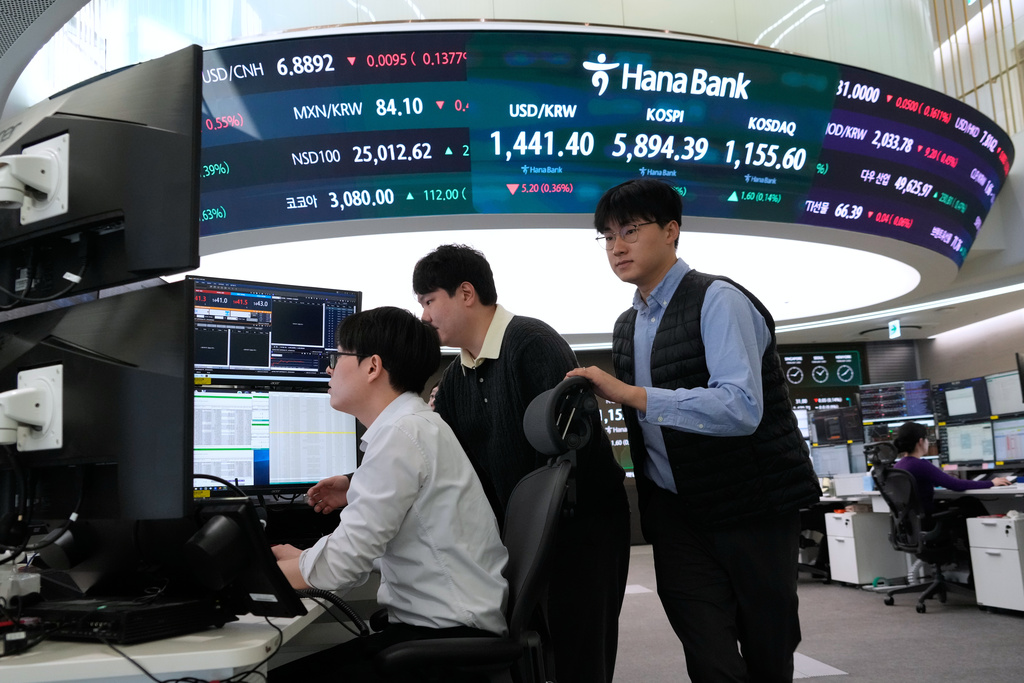 Currency traders work near a screen showing the Korea Composite Stock Price Index (KOSPI), top center, and the foreign exchange rate between U.S. dollar and South Korean won, top center left, at the foreign exchange dealing room of the Hana Bank headquarters in Seoul, South Korea, Monday, Feb. 23, 2026. (AP Photo/Ahn Young-joon)