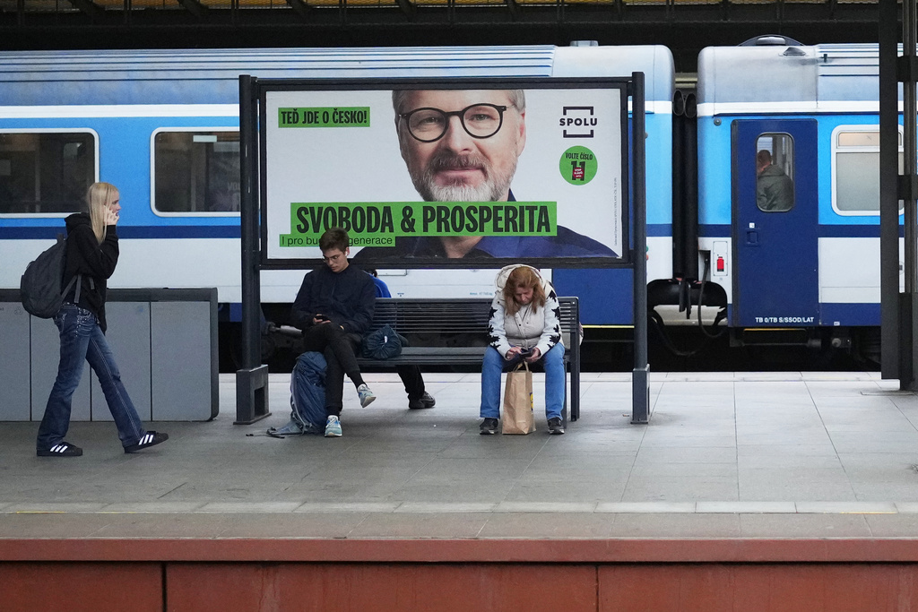 People sit by election posters ahead of Parliamentary elections in Prague, Czech Republic, Sept. 26, 2025. (AP Photo/Petr David Josek)