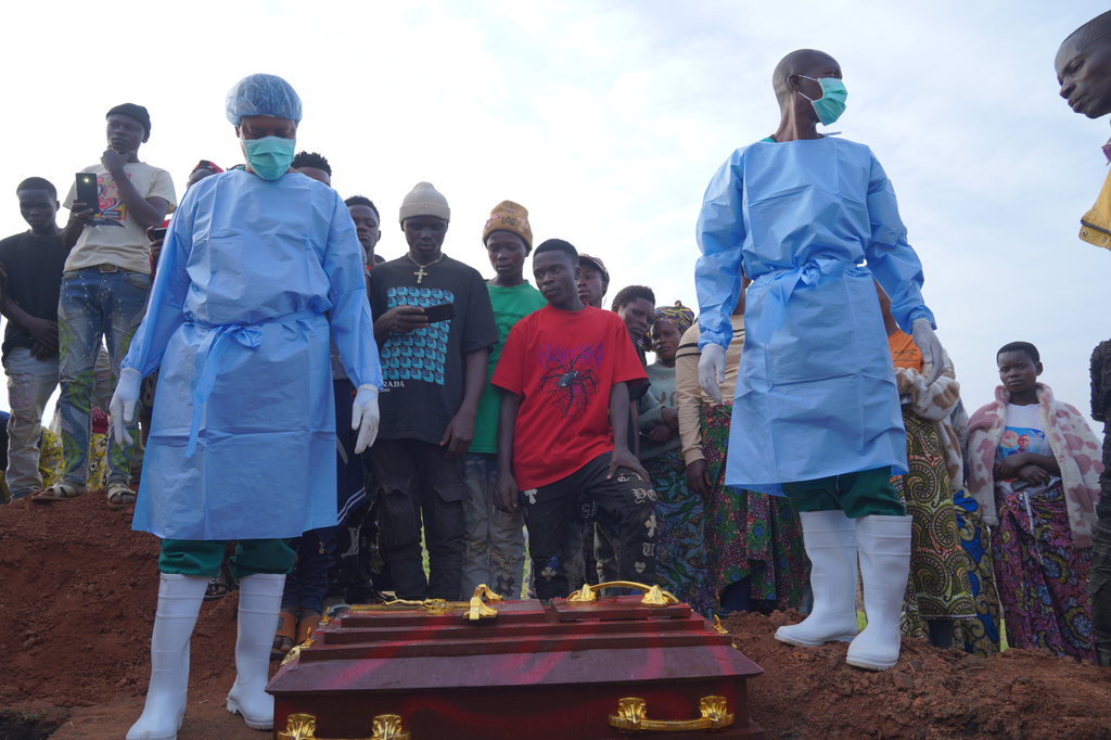 People dressed in protective gear prepare to lower into a grave the coffin containing the remains of 3-year-old Mave Mercienne, who died of Ebola, in Bunia, Ituri province, eastern Congo, Tuesday, Aug. 18, 2026. (AP Photo/Dieudonne Dirole)