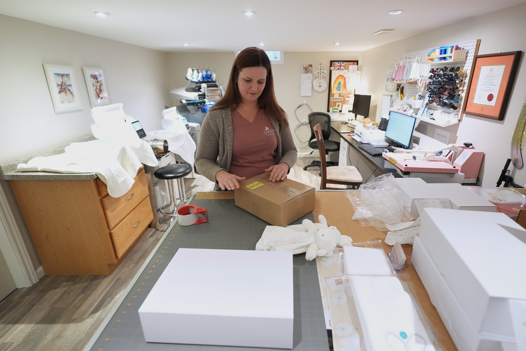 Sue Bacarro packages an order for shipping at her Etsy shop, Digi Wildflowers, Thursday, Oct. 30, 2025, in Windsor, Ontario, Canada. (AP Photo/Paul Sancya)