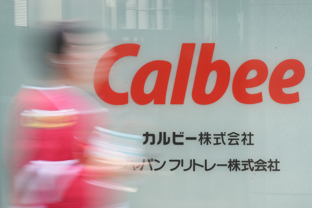 People walk past the logo of Calbee Inc., which makes potato chips and cereal, at its headquarters in Tokyo, Wednesday, May 13, 2026. (AP Photo/Eugene Hoshiko)