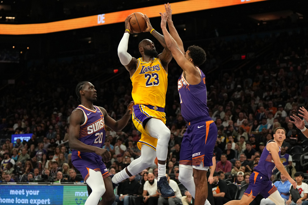 Los Angeles Lakers forward LeBron James drives between Phoenix Suns forward Rasheer Fleming (20) and forward Oso Ighodaro during the first half of an NBA basketball game, Thursday, Feb. 26, 2026, in Phoenix. (AP Photo/Rick Scuteri)
