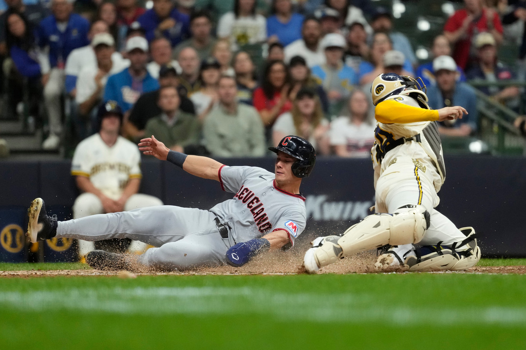 Cleveland Guardians' Stuart Fairchild, left, slides past Milwaukee Brewers' William Contreras to score a run during the seventh inning of a baseball game, Tuesday, June 16, 2026, in Milwaukee. (AP Photo/Aaron Gash)