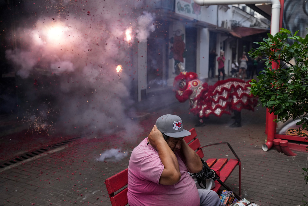 A man braces for the sound of firecrackers as people perform a lion dance to celebrate the Lunar New Year in Panama City, Wednesday, Feb. 18, 2026. (AP Photo/Matias Delacroix)