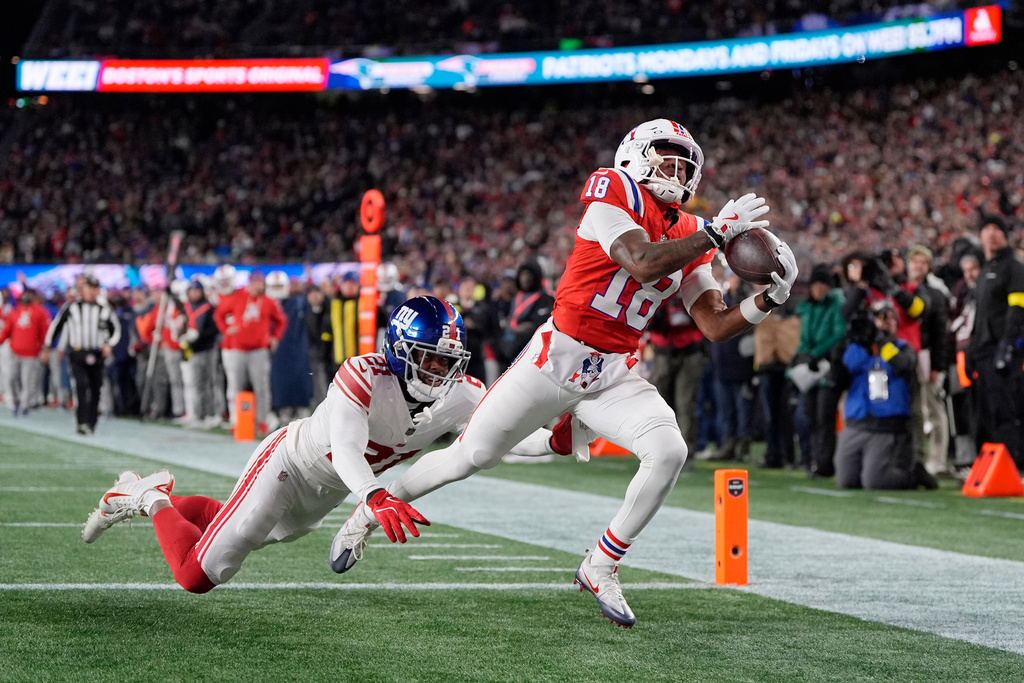 New England Patriots wide receiver Kyle Williams (18) catches a touchdown pass against New York Giants cornerback Paulson Adebo (21) during the first half of an NFL football game Monday, Dec. 1, 2025, in Foxborough, Mass. (AP Photo/Charles Krupa)