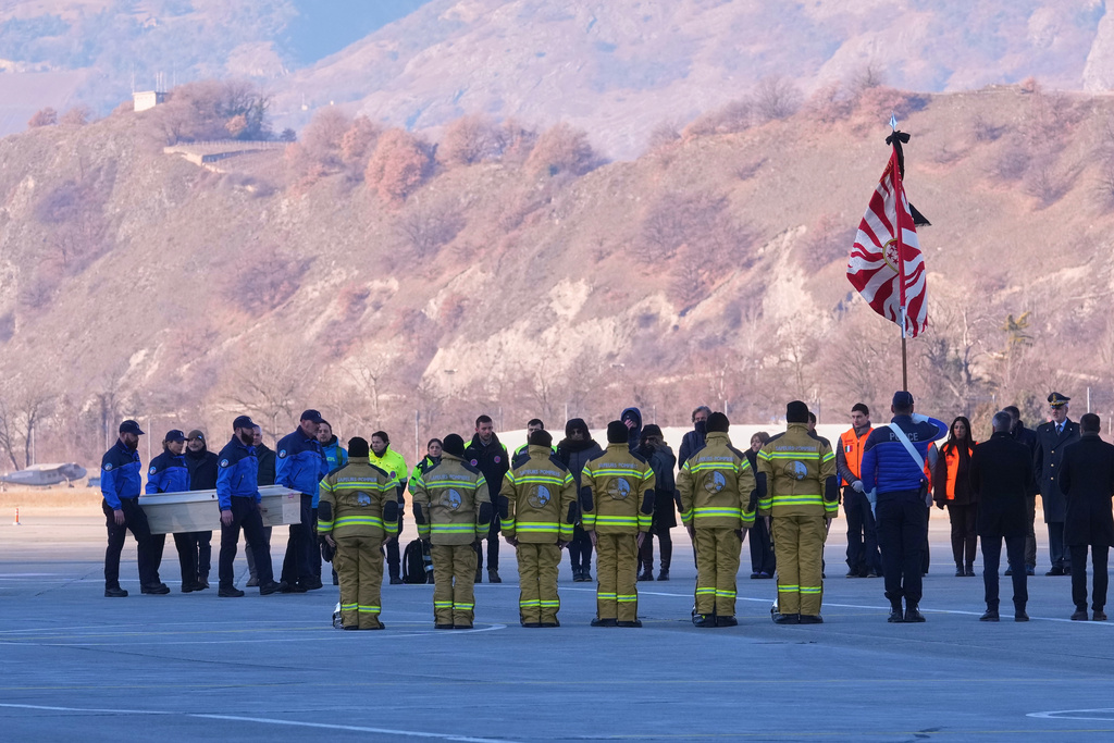 Police officers carry a coffin with a body of one of six Italians at the Military Airport in Sion, Swiss Alps, Switzerland, Monday, Jan. 5, 2026, following a devastating fire left dead and injured in a bar in Crans-Montana during the New Year's celebrations. (AP Photo/Antonio Calanni)