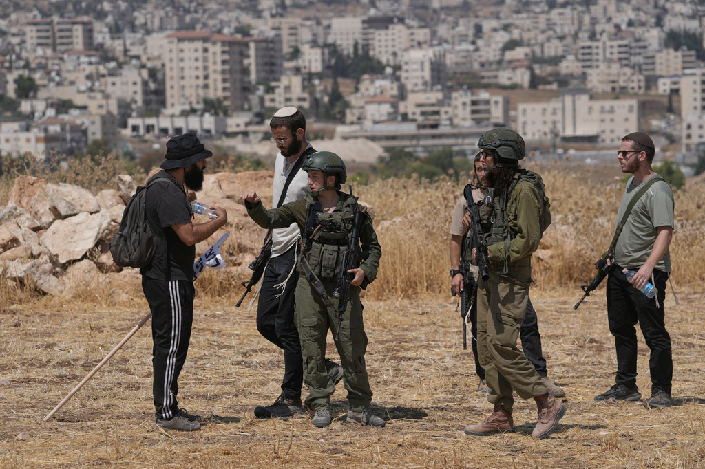 Israeli soldiers and settlers order Israeli and foreign peace activists to leave the site during a protest in support of local landowners whose property is threatened with seizure by Israeli settlers, on the outskirts of the West Bank city of Beit Sahour, Friday, Aug. 14, 2026. (AP Photo/Mahmoud Illean)