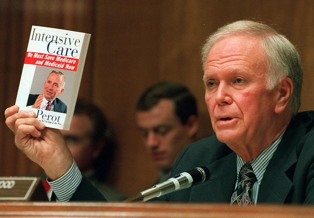 FILE - Senate Finance Committee Chairman Bob Packwood, R-Ore., holds a book entitled "Intensive Care" by Ross Perot, during hearings dealing with the future of Medicare on Capitol Hill, Aug. 30, 1995. (AP Photo/Dennis Cook, File)
