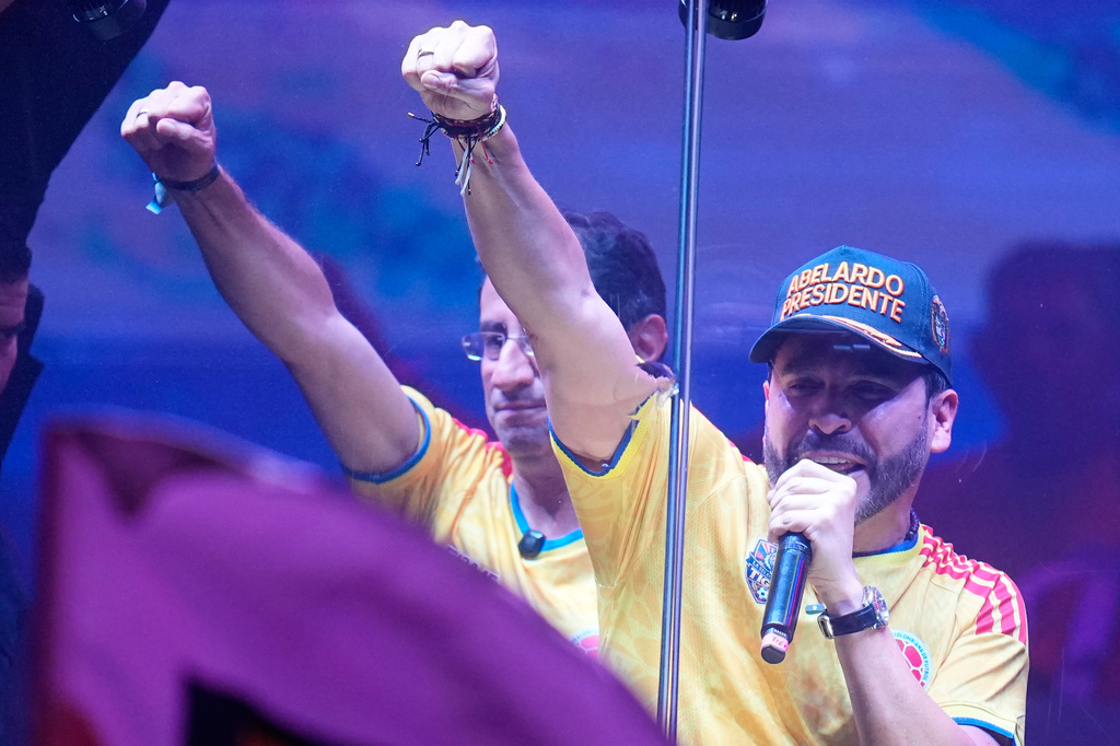 Presidential candidate Abelardo de la Espriella of the Defenders of the Motherland movement and his running mate Jose Manuel Restrepo, left, raise their fit from behind a bullet proof booth during a campaign rally in Barranquilla, Colombia, Saturday, May 23, 2026. (AP Photo/Fernando Vergara)