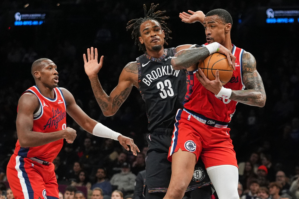LA Clippers' John Collins (20) and Kris Dunn (8) fights for control of the ball with Brooklyn Nets' Nic Claxton (33) during the first half of an NBA basketball game Friday, Jan. 9, 2026, in New York. (AP Photo/Frank Franklin II)