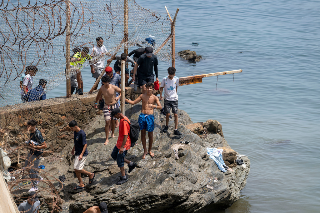FILE - People breach barbed wires as they attempt to cross from the Moroccan northern town of Fnideq to the Spanish enclave of Ceuta, July 31, 2026. (AP Photo, File)