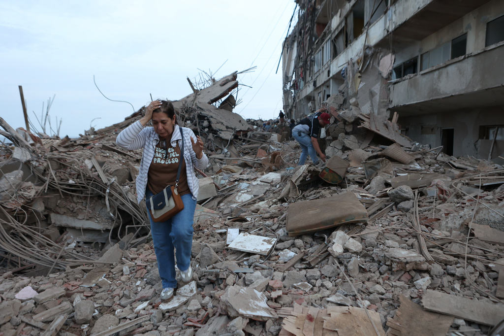 Dos mujeres caminan entre los escombros de edificios dañados por los sismos ocurridos el día anterior, el jueves 25 de junio de 2026, en Catia La Mar, Venezuela. (AP Foto/Pedro Mattey)