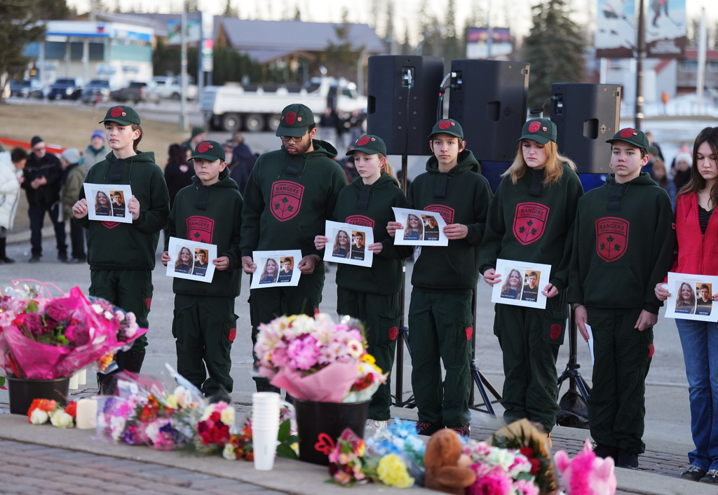 People hold photos of victims to a vigil for the victims of a mass shooting, in Tumbler Ridge, B.C., Friday, Feb. 13, 2026. (Christinne Muschi/The Canadian Press via AP)