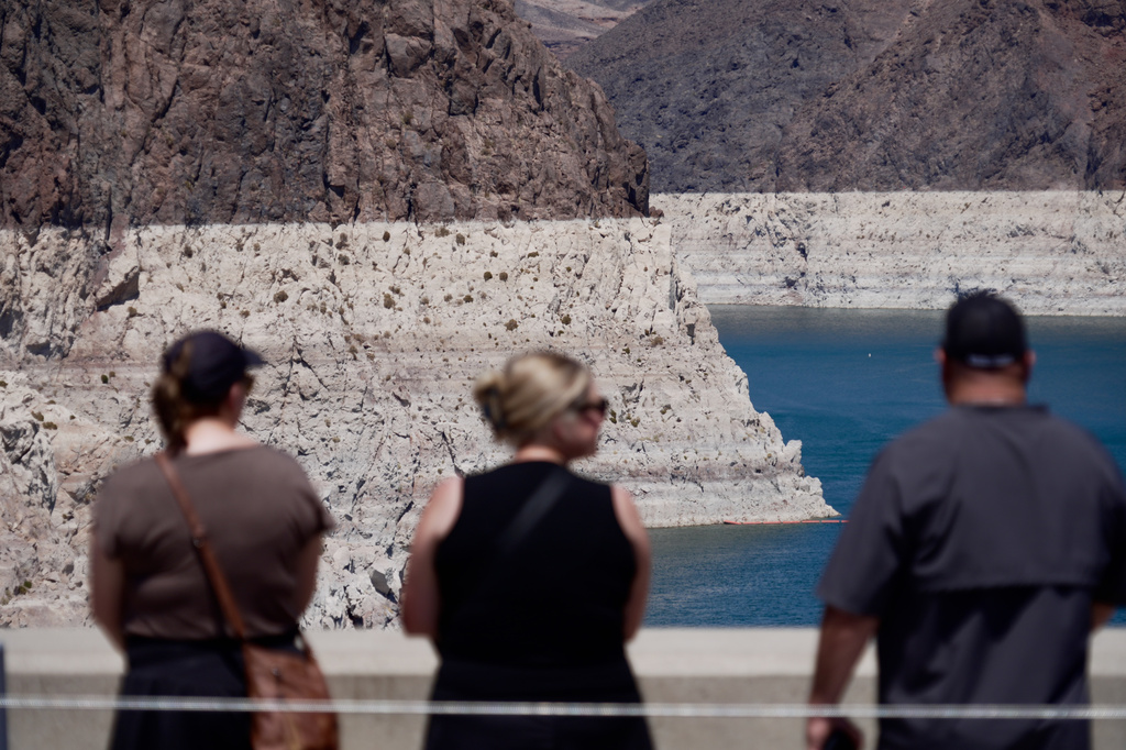 Tourists on the Hoover Dam look out at the bathtub ring of minerals that shows the former water levels of Lake Mead near Boulder City, Nev., on Friday, Aug. 7, 2026. (AP Photo/Ty ONeil)