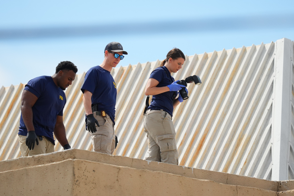 Law enforcement agents look around the roof of a building near the scene of a shooting at a U.S. Immigration and Customs Enforcement office in Dallas on Wednesday, Sept. 24, 2025. (AP Photo/Julio Cortez)